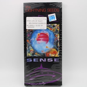 May include: A sealed VHS tape of "Sense" by The Lightning Seeds. The cover features a colorful, abstract design with a red planet and the band's name. The tracklist includes "The Life of Riley" and "Blowing Bubbles".