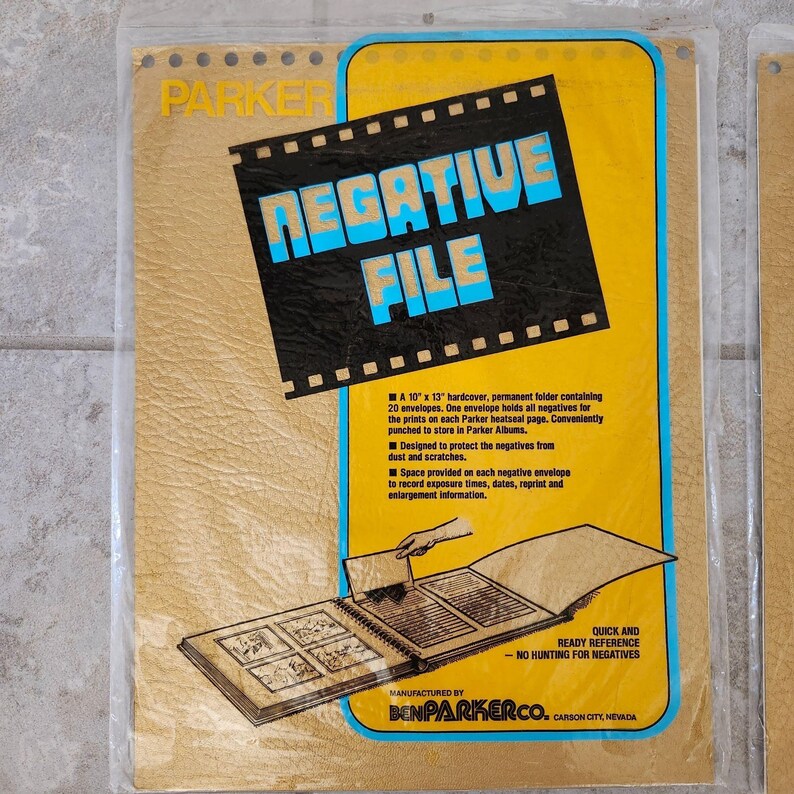 May include: A yellow and brown Parker Negative File folder with a black and blue film strip design. The folder is 10 inches by 13 inches and has 20 envelopes for storing negatives. It is designed to protect negatives from dust and scratches. The folder is manufactured by BenParkerCo. Carson City, Nevada.