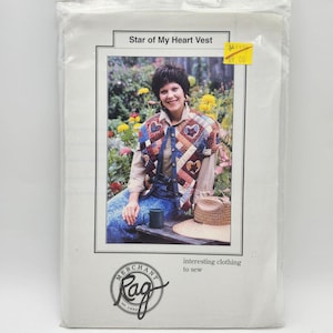 May include: A package for a vest pattern titled "Star of My Heart Vest." The image on the package shows a woman wearing the vest, which features heart-shaped patches in various colors. The package also includes the text "interesting clothing to sew."