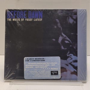 Puede incluir: CD precintado de "Before Dawn: The Music of Yusef Lateef". La portada es azul oscuro con texto blanco y un retrato. Una pegatina indica una reedición de edición limitada.