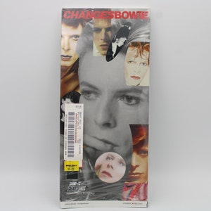 May include: A CD case with a collage of black and white images of David Bowie. The case is for the album "Changesbowie: Sound + Vision Greatest Hits". The text "BEST BUY CO" and "BEST BUY 10.99" are visible on the case.