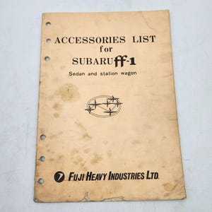 Puede incluir: Una lista de accesorios vintage para un Subaru ff-1 sedán y familiar. La portada es de color beige con texto negro y un logotipo. El documento tiene varios agujeros perforados en el borde izquierdo.