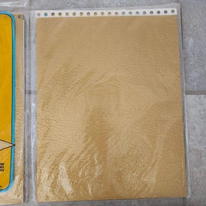 May include: A sheet of brown textured paper with a row of holes along the top edge. The paper is packaged in a clear plastic sleeve.