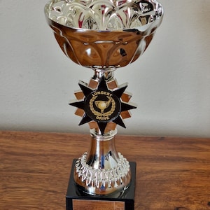 Personalised nearest the pin or longest drive chrome golf trophy cup on black marble base. 16 cm tall.