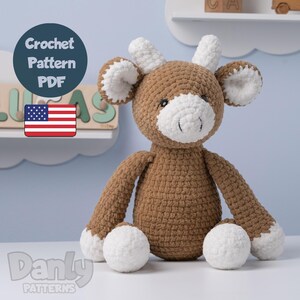 May include: A handmade brown and white crochet deer plushie with a friendly expression. The deer has white accents on its ears, antlers, and feet. The image includes a "Crochet Pattern PDF" graphic and a US flag, indicating the pattern's origin.