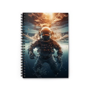 May include: Spiral-bound notebook featuring an astronaut submerged in water. The astronaut is wearing a spacesuit and helmet, with water and bubbles surrounding them. The background shows a bright, sunlit surface.