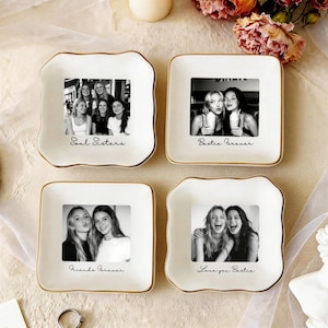 May include: Four white ceramic trinket dishes with gold rims, each featuring a black and white photo and a handwritten phrase. The phrases include "Soul Sisters," "Bestie Forever," "Friends Forever," and "Love you Bestie."