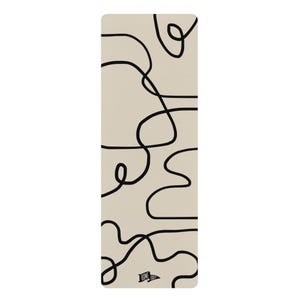 May include: A rectangular yoga mat with a beige background and a black abstract line design. The mat has rounded corners and a small white flag with the word "HOME" printed on it.
