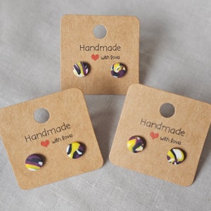 May include: Three pairs of handmade stud earrings with a colourful abstract pattern. The earrings are displayed on brown cards with the text "Handmade with love".