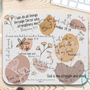 May include: A beige and brown mousepad with inspirational bible verses and floral illustrations. The text includes "I can do all things through Christ who strengthens me", "The Lord will fight for me", "I will trust in the Lord with all my heart", "God is my strength and shield", and more.