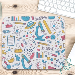 May include: A rectangular mouse pad featuring a repeating pattern of science-themed illustrations including blue microscopes, yellow rulers, colorful chemical flasks, DNA strands, atoms, bacteria, pencils, and bar charts on a light gray background.
