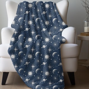 May include: A navy blue throw blanket with a white celestial pattern featuring moons, stars, and planets.