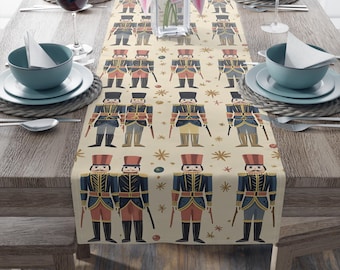 May include: A beige table runner with a repeating pattern of toy soldiers in red, blue, and black uniforms. The runner is decorated with small star and dot accents. The table is set with plates, bowls, and wine glasses.