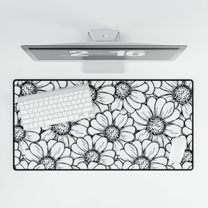 May include: A rectangular desk mat featuring a black and white floral pattern with a white keyboard and mouse. The mat is positioned beneath a computer monitor.