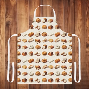 May include: A white apron featuring a pattern of different breads and rolls. The apron has adjustable straps and a pocket.