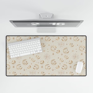 May include: A beige desk mat with a gold moon and star pattern. A white keyboard and mouse are on the mat.