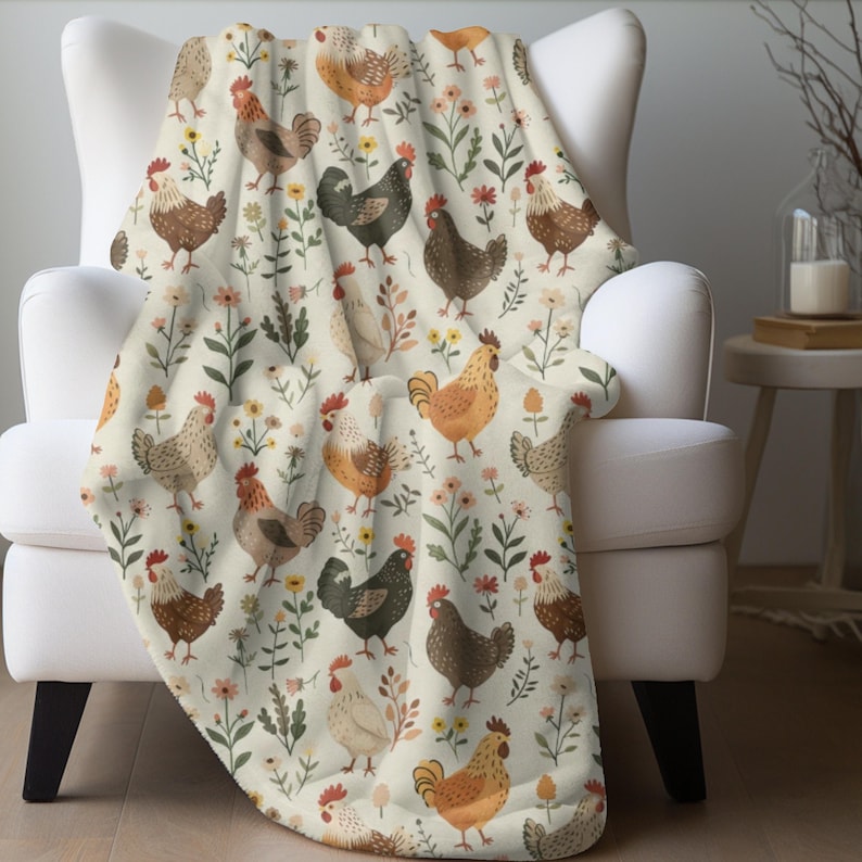 May include: A cream-colored throw blanket with a repeating pattern of brown, white, and black chickens and green and pink flowers.