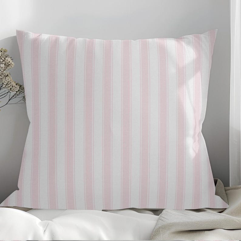 May include: A square pillowcase with a vertical stripe pattern in soft pink and white. The pillowcase is made of a smooth fabric and is likely for a bed or decorative use.