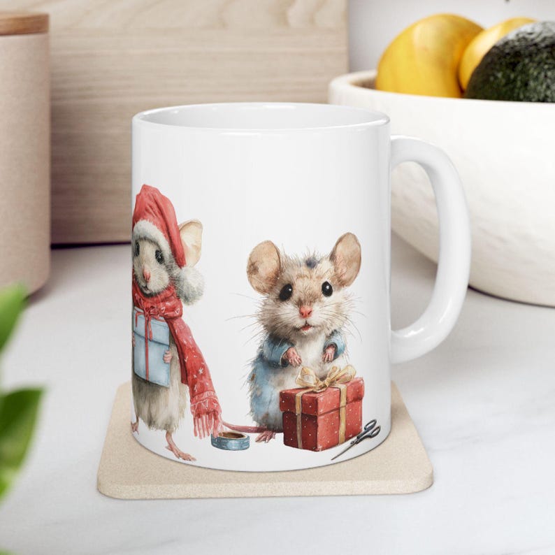 May include: White ceramic mug featuring watercolor illustrations of two mice. One mouse wears a Santa hat and red scarf, holding a blue gift. The other mouse wears a blue jacket and holds a red gift box. A festive holiday theme.