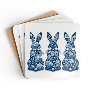 May include: Three blue and white ceramic bunny coasters with floral designs. The bunnies are facing forward and have a bow tied around their necks.