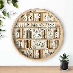 May include: Round wooden wall clock featuring a bookshelf design with books and floral accents. The clock face displays white numbers and hands, with a light wood frame. The clock is a decorative item for home decor.