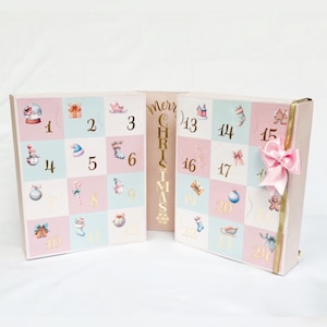 Könnte beinhalten: Ein rosa-blauer Weihnachts-Adventskalender mit 24 nummerierten Türen. Jede Tür zeigt eine andere festliche Illustration. Der Kalender ist geöffnet, um die Türen hinter den Nummern 13 bis 24 zu zeigen. Die Worte "Frohe Weihnachten" sind in Gold an der Seite des Kalenders gedruckt.