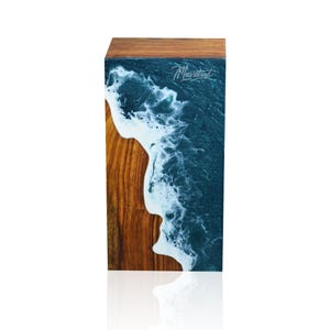 May include: A wooden block with a teal and white resin pour, resembling an ocean wave. The block is signed "Maxwood" in the top right corner.