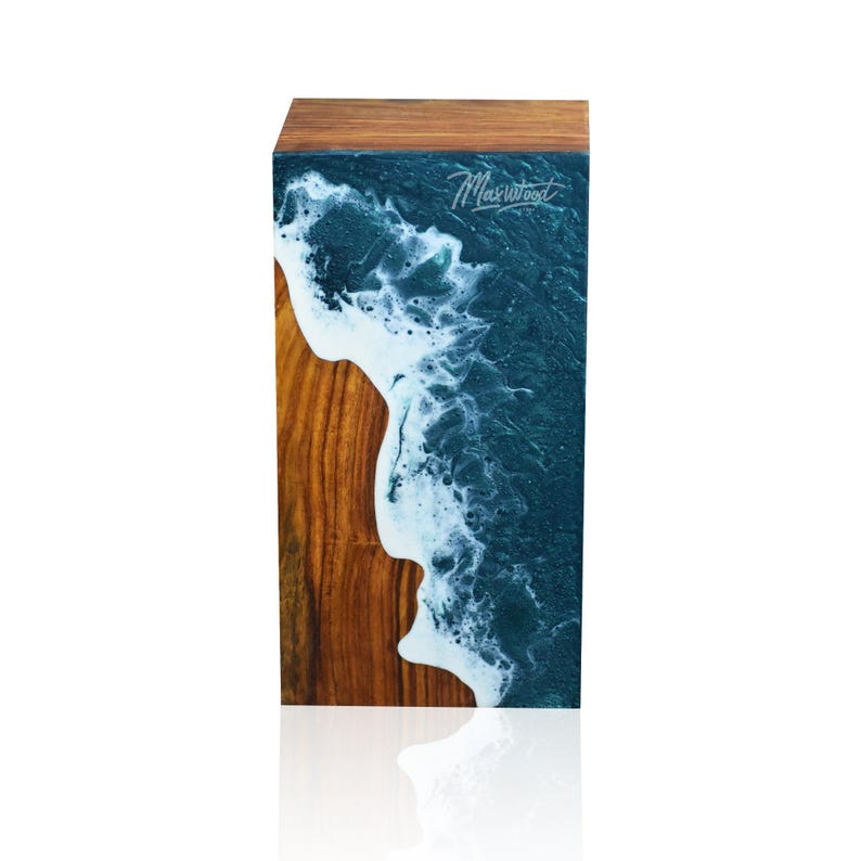 May include: A wooden block with a teal and white resin pour, resembling an ocean wave. The block is signed "Maxwood" in the top right corner.