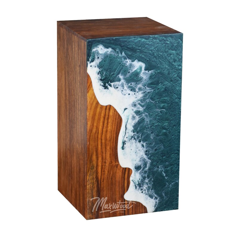 May include: A wooden cube with a teal and white resin wave design. The cube is made of walnut wood and has a natural wood finish. The resin wave design is on one side of the cube and is a unique and eye-catching feature. The cube is signed "Maxwood" on the bottom.