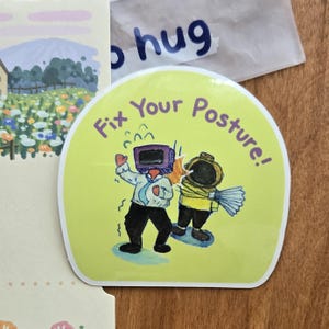 May include: A circular sticker with a pale green backdrop displays two cartoon characters. One has a TV for a head, the other wears a diving helmet. The sticker has the words "Fix Your Posture!" in purple lettering.