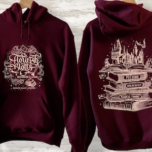 May include: Burgundy hoodie with a white graphic of the Flourish and Blotts bookstore logo on the front and a stack of books with the Hogwarts castle in the background on the back.