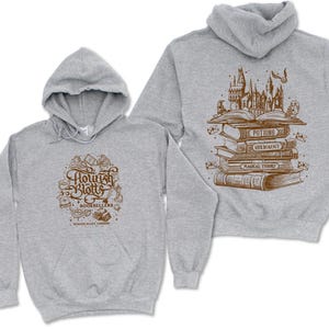 May include: A gray hoodie with a graphic of a stack of books and the text "Flourish and Blotts Booksellers" on the front. The back of the hoodie has a graphic of a stack of books with the text "Potions, Herbology, Magical Theory" on the spines.