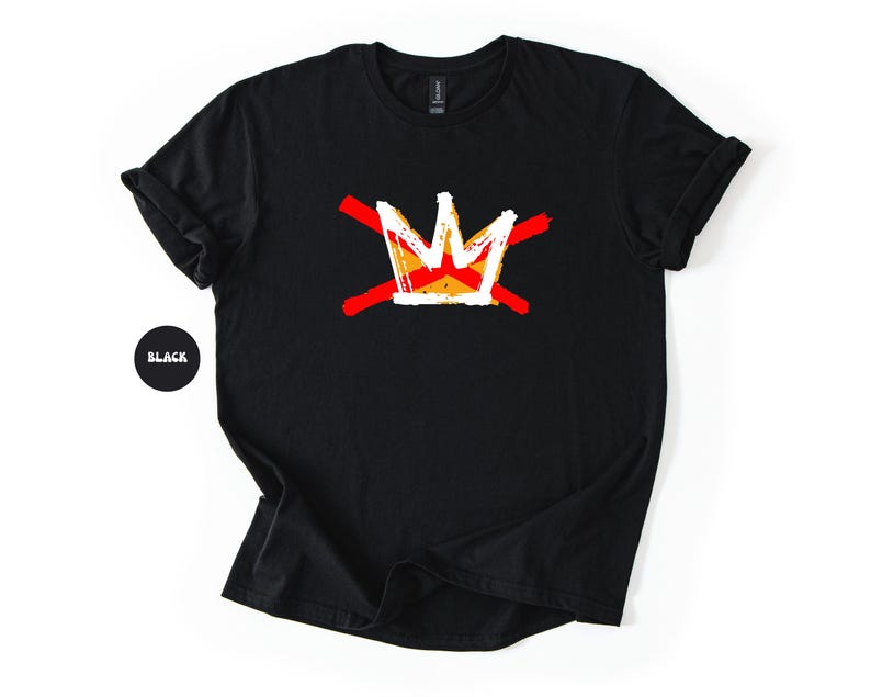 May include: Black t-shirt featuring a white and orange crown design crossed by two red lines. The crown has a yellow and orange center. The shirt is made of a soft material and has a crew neck.