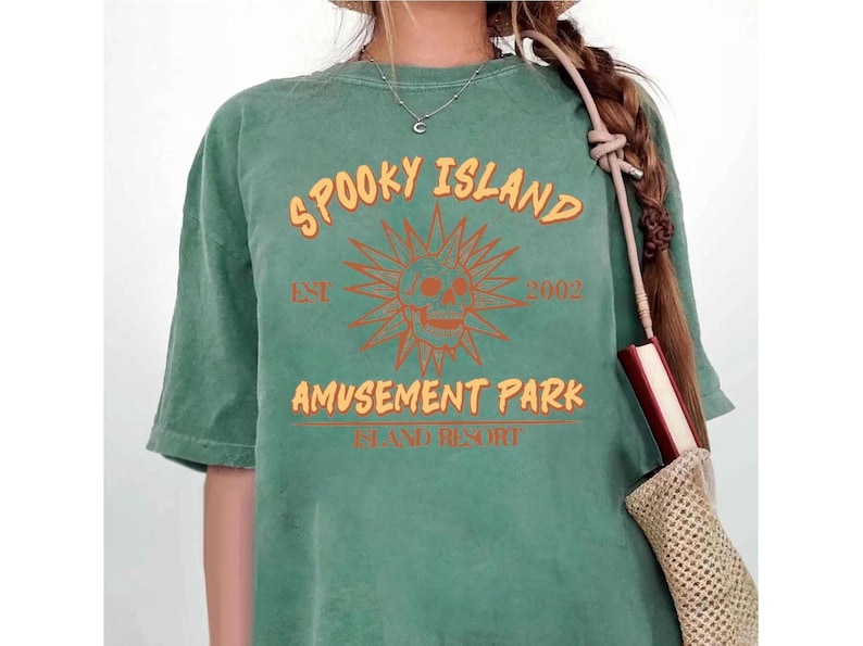 A person wearing a green t-shirt with the text "Spooky Island Amusement Park" printed on it.