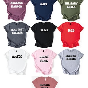 May include: A color chart of Gildan t-shirts in various colors, including Heather Maroon, Navy, Military Green, Dark Grey Heather, Black, Red, White, Light Pink, and Athletic Heather. The text "GILDAN COLOR CHART" is at the top.