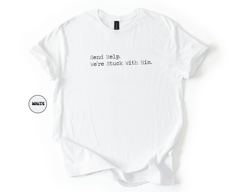 Pu&ograve; includere: T-shirt bianca con la scritta "Send Help. We're Stuck With Him." stampata in nero. La maglietta ha girocollo e maniche corte. La parola "WHITE" &egrave; in un cerchio bianco in basso a sinistra.