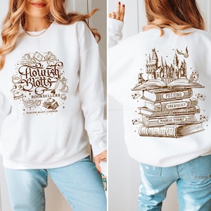 May include: White sweatshirt with a brown graphic print of the text "Flourish and Blotts Booksellers Diagon Alley London" on the front and a brown graphic print of a stack of books with the text "Potions, Herbology, Magical Theory" on the back.