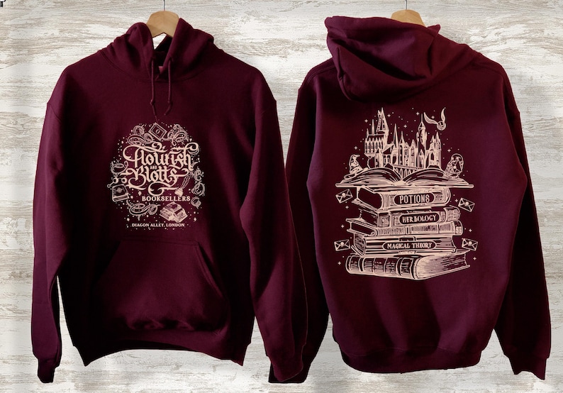May include: Burgundy hoodie with a white graphic of the Flourish and Blotts bookstore logo on the front and a stack of books with the Hogwarts castle in the background on the back.