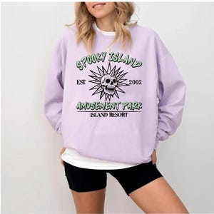 A woman wearing a purple sweatshirt with a graphic design and text printed on it.