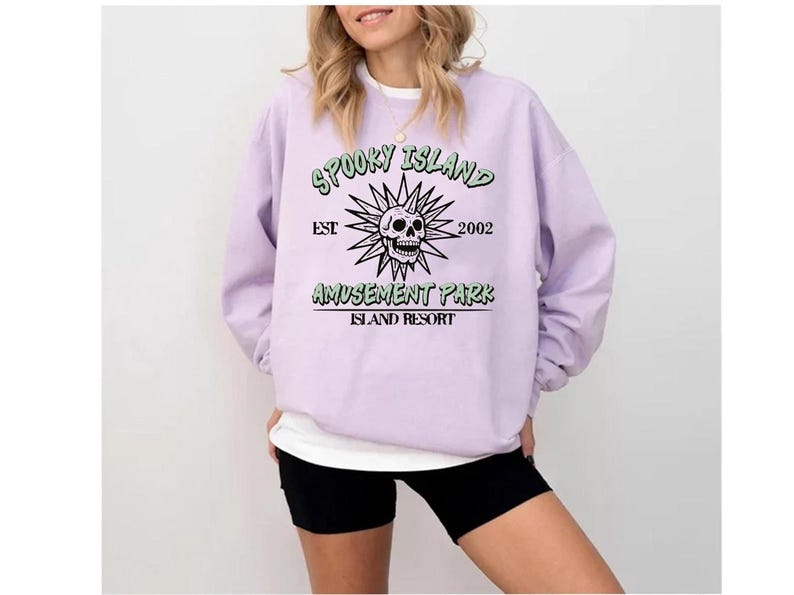 A woman wearing a purple sweatshirt with a graphic design and text printed on it.