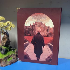 May include: A burgundy-colored book cover with a printed illustration. The image depicts a person walking towards a large building. Text on the cover reads, "ONCE UPON A TIME THERE HAD BEEN A GIRL WHO FOUGHT IN A WAR..."