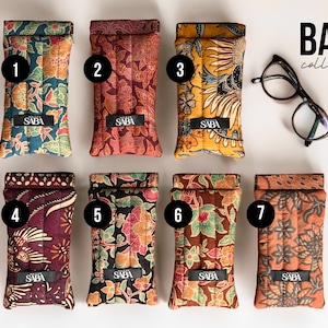 May include: Seven colorful patterned eyeglass cases with the word "SABA" printed on each case. The cases are numbered 1 through 7. The text "BALI collection" is printed in the upper right corner of the image.