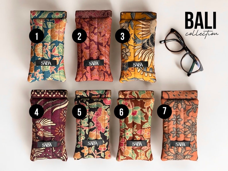 May include: Seven colorful patterned eyeglass cases with the word "SABA" printed on each case. The cases are numbered 1 through 7. The text "BALI collection" is printed in the upper right corner of the image.