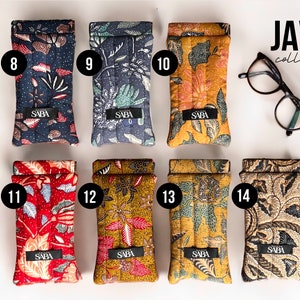 May include: Eight different patterned eyeglass cases with the word "SABA" printed on each. The cases are arranged in two rows of four. The cases are all made of fabric and have a quilted design. The word "JAVA collection" is printed in the top right corner of the image.