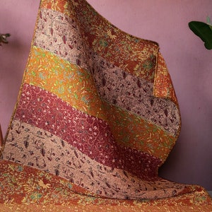 May include: A multi-colored patchwork quilt with a floral pattern. The quilt is made of different fabrics in shades of brown, orange, and red.