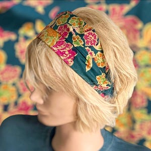 Peut inclure: Un bandeau bleu sarcelle avec un motif floral dans des tons de rose, jaune et vert. Le bandeau est en tissu et a une sensation douce et confortable.
