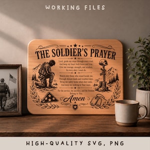 Puede incluir: Una placa de madera rectangular con el texto grabado THE SOLDIER'S PRAYER, un soldado arrodillado, un rifle con casco, una bandera plegada y placas de identificación. El diseño incluye montañas y ramas de laurel en un tono marrón oscuro.