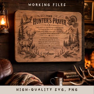 May include: A rectangular wooden sign featuring the engraved text THE HUNTER'S PRAYER, accompanied by illustrations of a deer, a bird, pine trees, and mountains. The design includes decorative flourishes and the word Amen at the bottom.