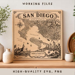 Może przedstawiać: Kwadratowa drewniana dekoracja ścienna z wygrawerowaną czarną mapą San Diego w Kalifornii. Projekt zawiera różę wiatrów, napis San Diego, California, USA, współrzędne geograficzne oraz frazę America's Finest City, Est. 1769.