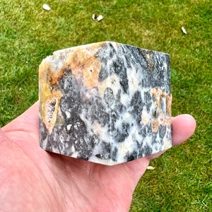 May include: A close-up of a black, white and yellow patterned stone. The stone has a rough, textured surface.